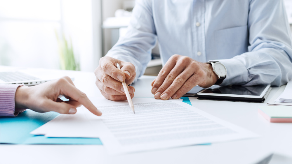 Person reviewing an insurance plan document or Certificate of Coverage at a table, reading closely.